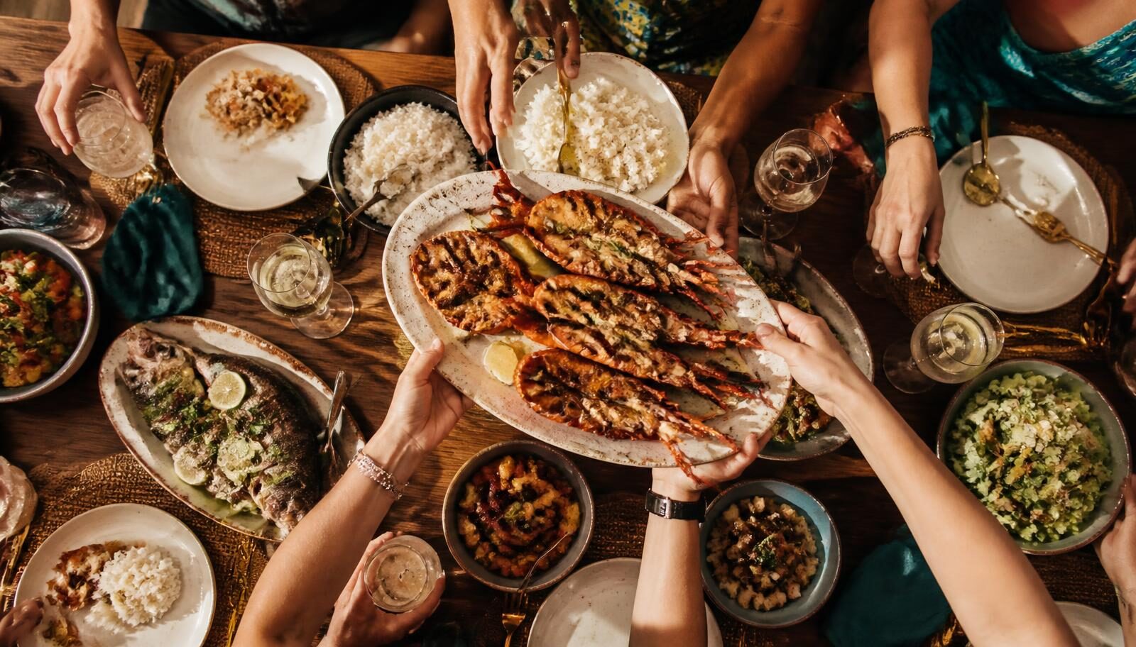 Shared plates and glasses being passed around a busy group restaurant table