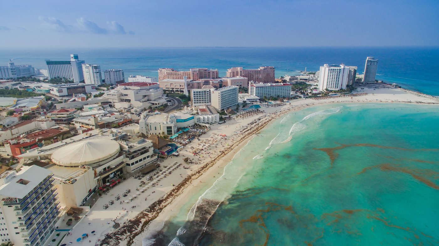 Calm turquoise shallows and soft white sand shoreline lined with palm trees