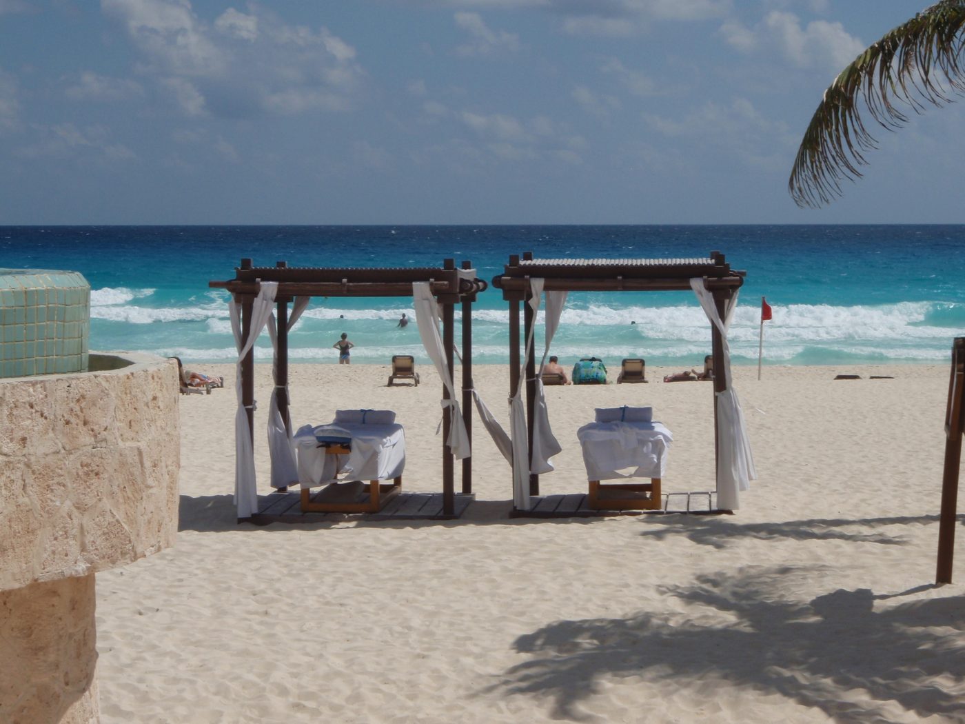 Palm trees leaning over turquoise shallow water on a wide white sand Caribbean beach