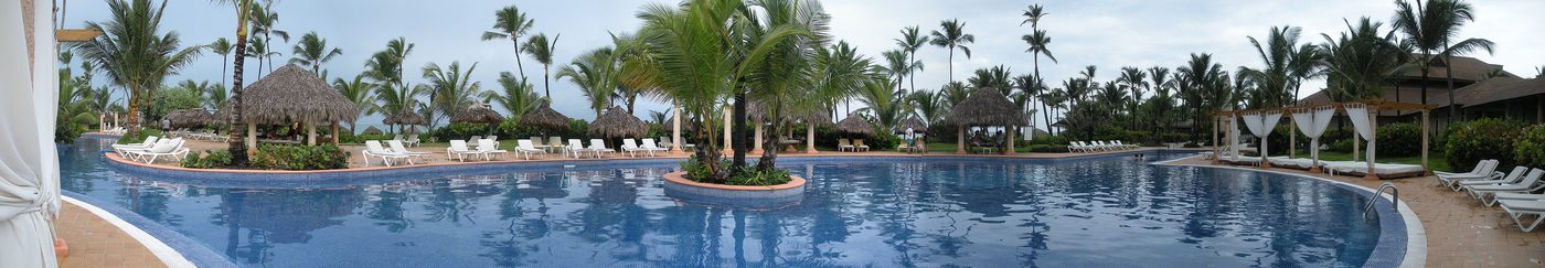 Pool party scene at a resort with a DJ setup near the water
