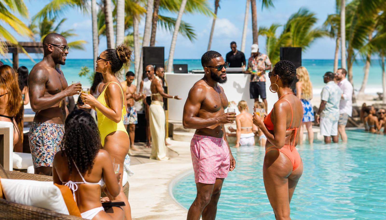 Stylish adults celebrating at a resort pool party with drinks and tropical decor
