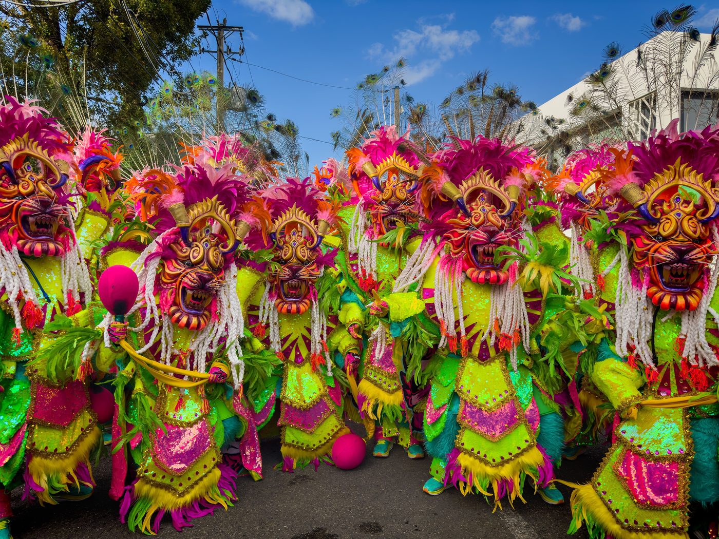 Group of Dominican carnival performers in bright horned Lechon masks and sequined costumes during a parade