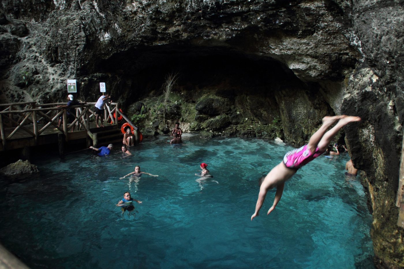 Turquoise cenote pool surrounded by limestone cliffs and jungle