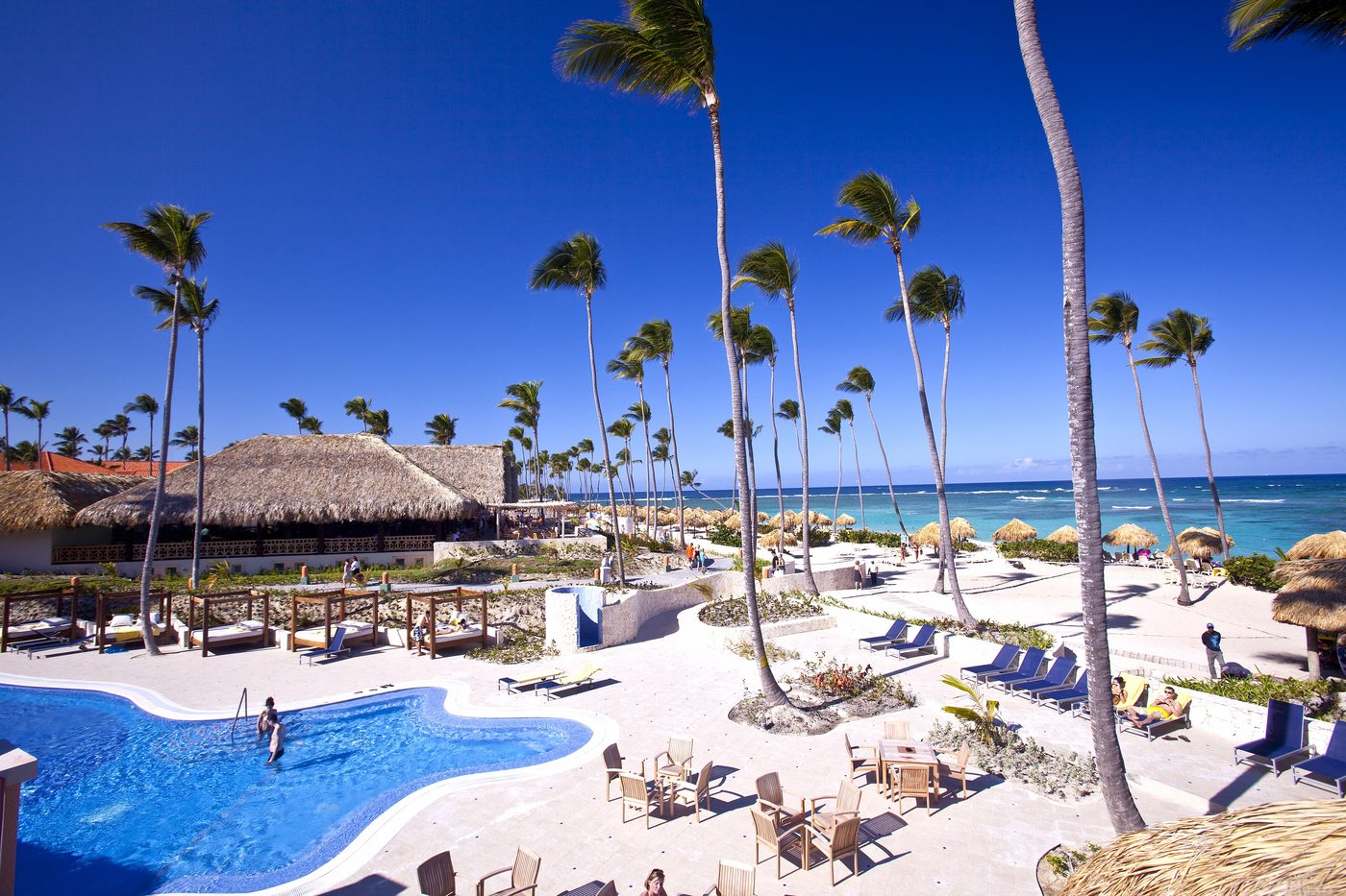 Beach umbrellas and sun loungers lined up on the sand beside calm Caribbean water