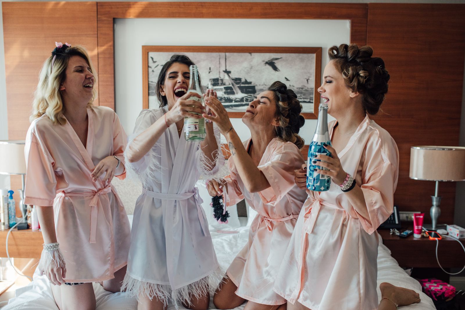 Women in robes toasting with champagne while getting ready in a hotel room
