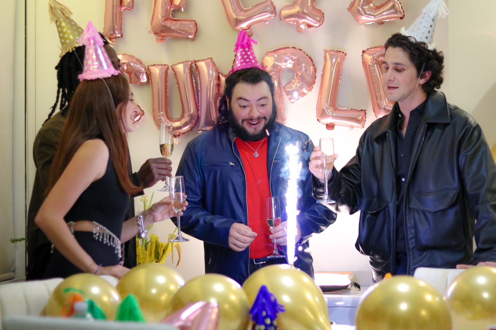 A diverse group of adult friends celebrating with champagne, balloons and a sparkler