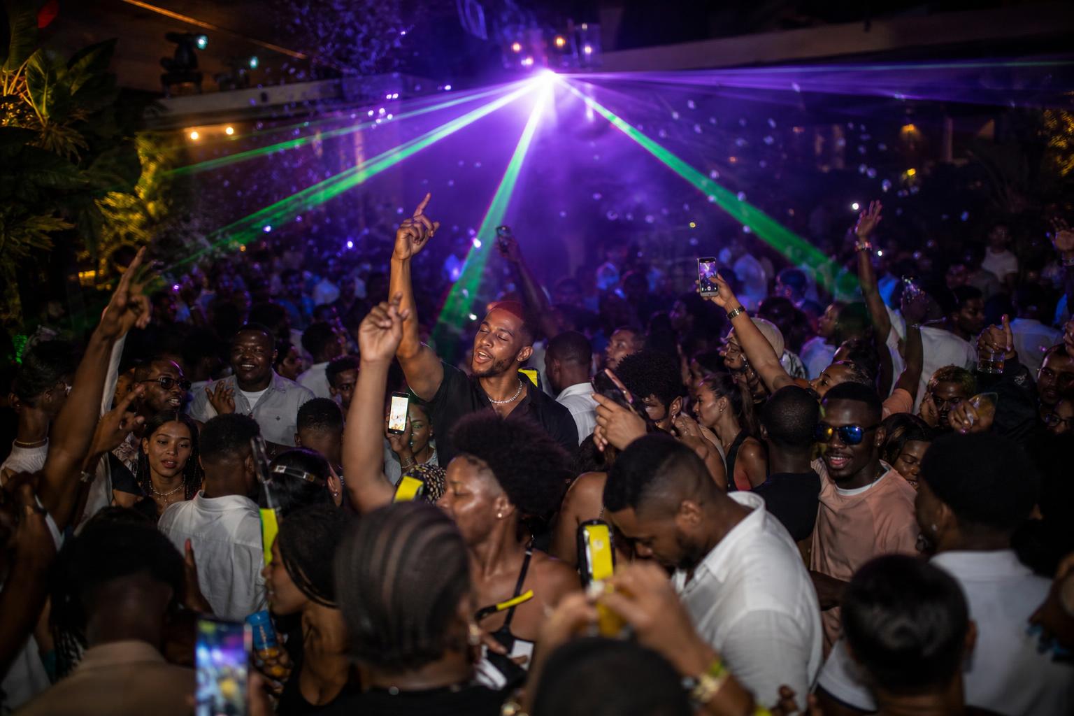 Nightclub dance floor under laser lights with a celebrating crowd